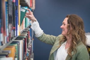 student pulling a book off the shelf