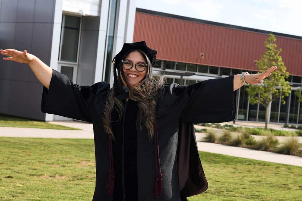 female chiropractic graduate of Sherman College with hands raised