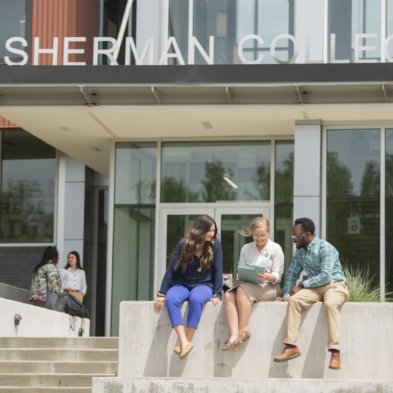 Students sitting outside of Sherman College building